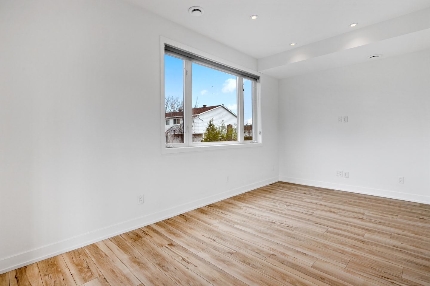 Leerer moderner Raum mit Holzboden und großem Fenster.