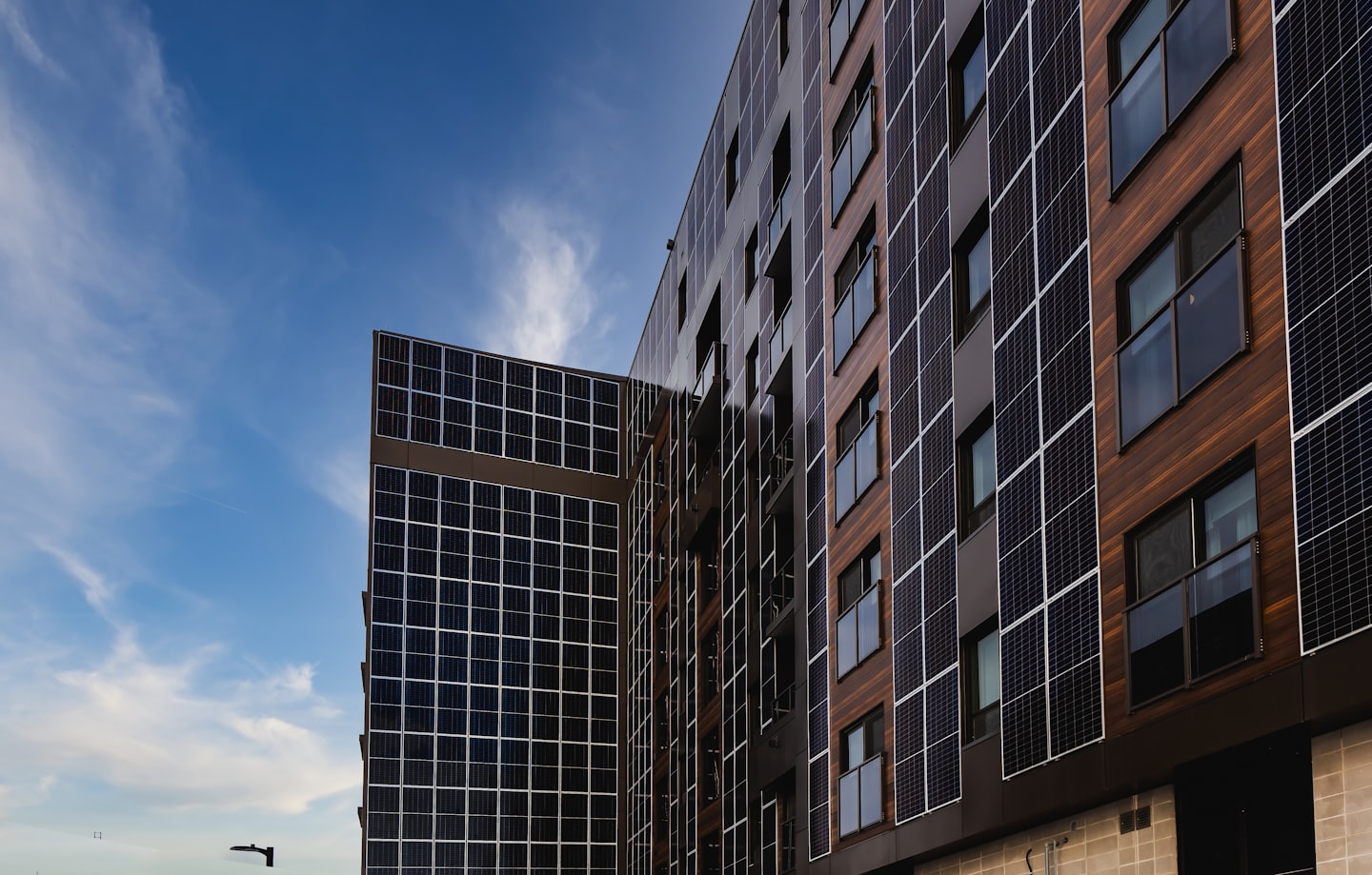 Moderne Gebäudefassade mit Solaranlagen und Holzverkleidung.